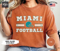 Miami Football Shirt Dolphin Football Gameday Shirt Miami Football Apparel Miami Sports Apparel Retro Dolphin Football Fan Gift Idea Graphic Tee – Bold Style · Trending Graphic Apparel